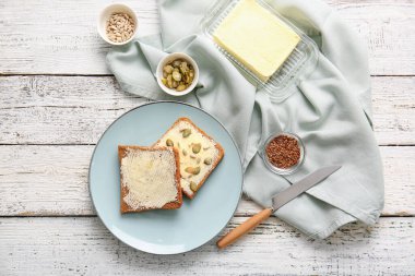 Hafif ahşap arka planda tereyağlı ve tohumlu taze ekmek dilimleri