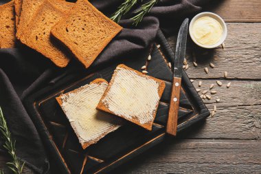 Tahta zemin üzerinde tereyağı ve ayçekirdeği olan taze ekmek dilimleri.