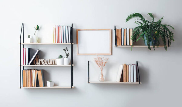 Shelves with books and decor hanging on light wall