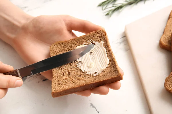 Kobieta Rozkładająca Masło Plasterek Świeżego Chleba Jasnym Tle Zbliżenie — Zdjęcie stockowe