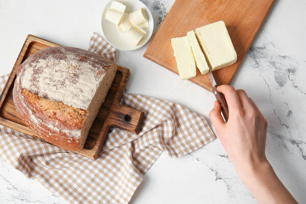 Woman cutting fresh butter on wooden board