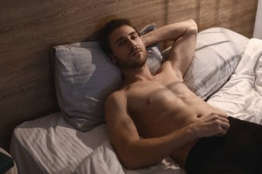 Geceleri yatakta yatan seksi genç adam.