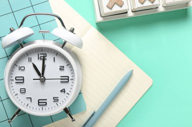 Alarm saati, not defterleri ve renk arkaplanı üzerindeki kalem, kapat