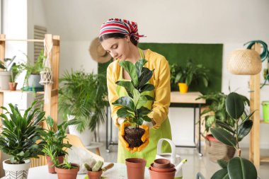 Evde çiçekleriyle ilgilenen genç bir kadın.