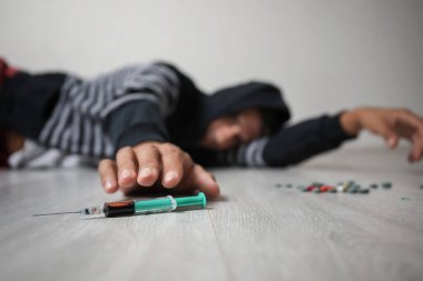 Şırıngalı bir erkek bağımlı yerde yatıyor.