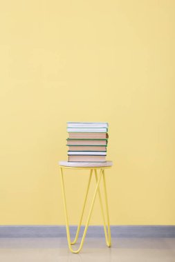 Renk arkaplanı üzerine kitap yığını olan sandalye