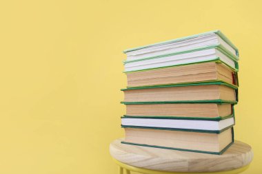 Renk arkaplanı üzerine kitap yığınına sahip sandalye, yakın plan