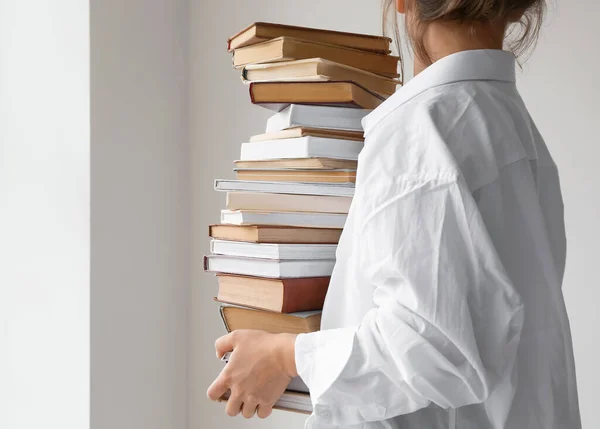 Woman with stack of books on light background, closeup