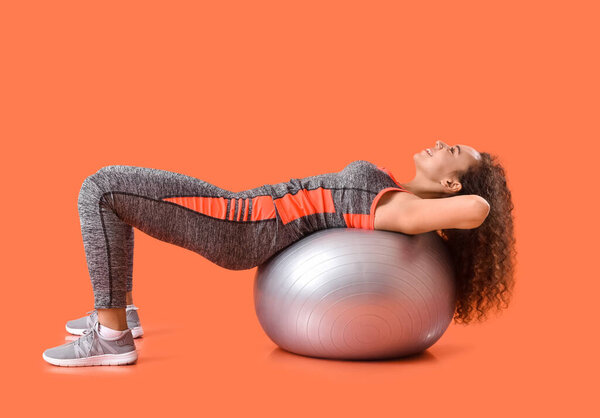 Красивая молодая женщина тренировки с фитнес-мяч на цветном фоне