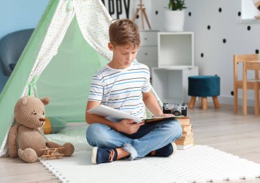 Evde kitap okuyan şirin bir çocuk.