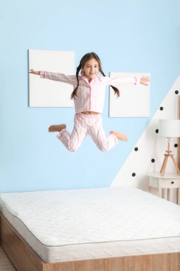 Yatakta zıplayan komik küçük kız