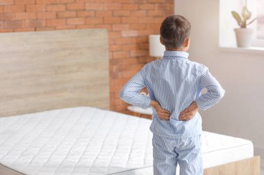 Küçük çocuk rahatsız edici yatak yüzünden sabahları sırt ağrısı çekiyor.