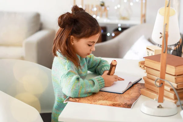 可爱的小女孩在家里的笔记本上写字 — 图库照片
