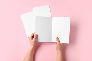 Renk arkaplanı üzerine boş broşürleri olan eller