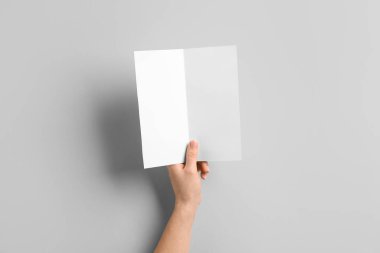 Işık arkaplanı üzerine boş broşür ile el.