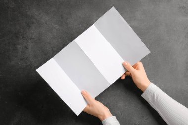 Koyu arkaplanda boş broşür olan eller