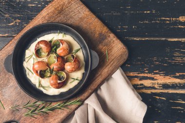 Koyu ahşap arka planda lezzetli salyangozlu kızartma tavası.