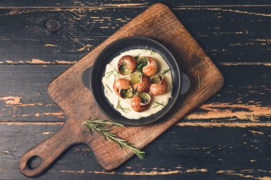 Koyu ahşap arka planda lezzetli salyangozlu kızartma tavası.