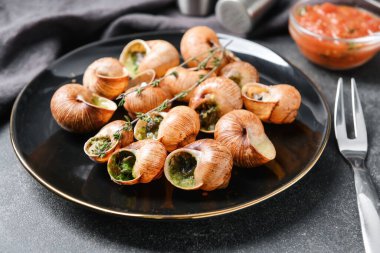 Koyu arkaplanda lezzetli salyangozlu tabak