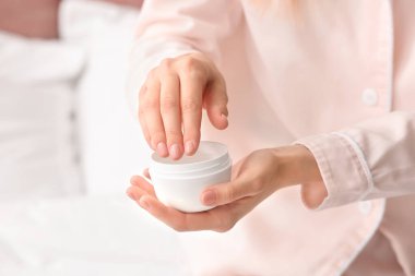 Genç bir kadın ellerine krem sürüyor, yakın plan.