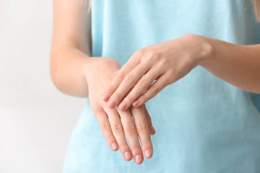 Genç bir kadın ellerine krem sürüyor, yakın plan.