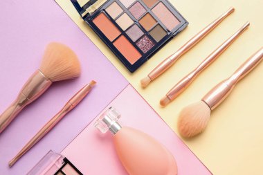 Renkli arkaplanda şık makyaj fırçaları ve kozmetik ürünleri