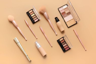 Renkli arkaplanda şık makyaj fırçaları ve kozmetik ürünleri