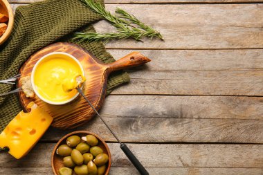 Tahta arka planda peynir fondüsüne batırılmış kızarmış ekmeğe yapış.