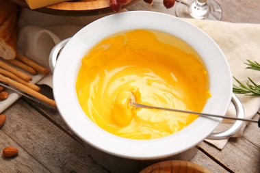 Tahta arka planda peynir fondüsüne batırılmış kızarmış ekmeğe yapış.