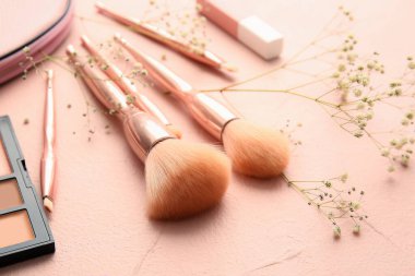 Renk arkaplanında makyaj fırçaları ve kozmetik ürünleri