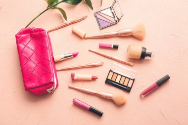 Renk arkaplanında makyaj fırçası ve kozmetik ürünleri olan çanta