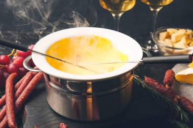 Peynir fondü ve koyu arkaplanda farklı atıştırmalıklar.