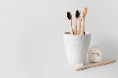 Beyaz arka planda diş fırçası ve diş ipi olan tutucu