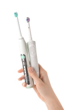 Beyaz arka planda elektrikli diş fırçası olan bir kadın el.