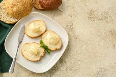 Taze ekmek dilimleri, arkaplanda tereyağı ve bıçak var.