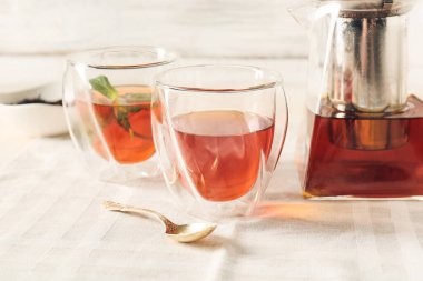 Hafif arkaplanda çaydanlık ve bardaklar dolusu sıcak içecek