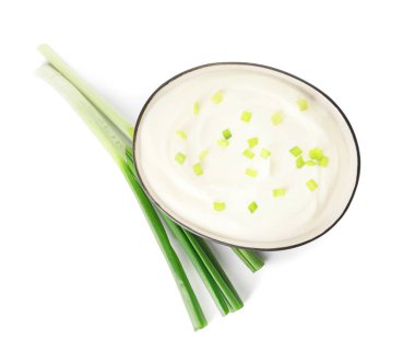 Beyaz arka planda bir kase ekşi krema ve yeşil soğan.