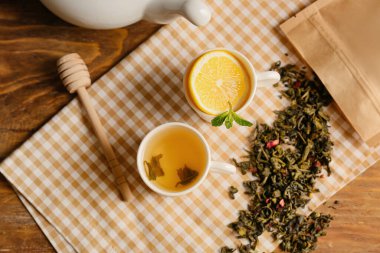 Bardaklar ve çaydanlık yeşil çay, ahşap arka planda limon.