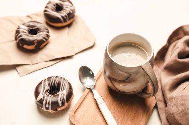 Hafif arka planda donutlu bir fincan kahve.