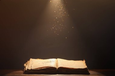 Masadaki eski kitabı koyu arkaplana karşı aç