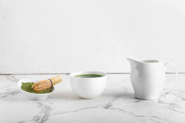 Bir fincan kibrit çayı, süt, toz ve chasen hafif arka planda.