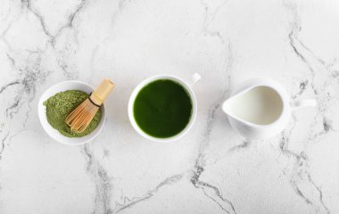 Bir fincan kibrit çayı, süt, toz ve chasen hafif arka planda.