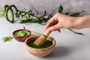 Kadın arka planda matcha çayı hazırlıyor