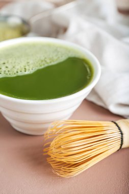 Renkli arka planda bir kase kibrit çayı ve chasen, yakın plan