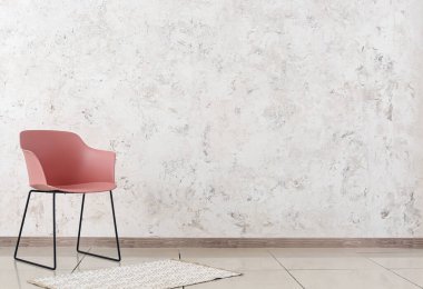 Odada duvarda halı olan modern bir koltuk.