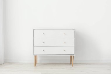 Çekmecelerin modern sandığı, odanın ışık duvarının yanında.