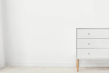 Çekmecelerin modern sandığı, odanın ışık duvarının yanında.