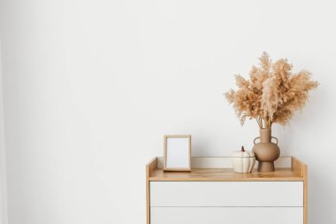 Çekmecelerin modern sandığı, odanın ışık duvarının yanında.