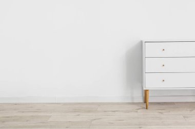 Çekmecelerin modern sandığı, odanın ışık duvarının yanında.