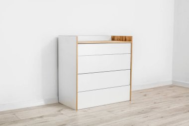 Çekmecelerin modern sandığı, odanın ışık duvarının yanında.